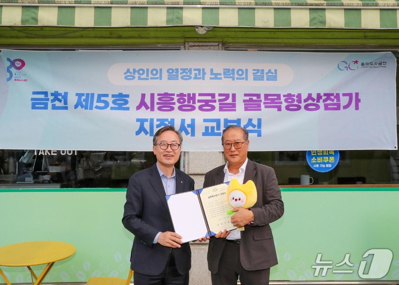 유성훈 금천구청장(왼쪽)과 김명식 상인회장이 골목형상점가 지정서 교부식을 진행하고 기념촬영을 하고 있다.(금천구 제공)