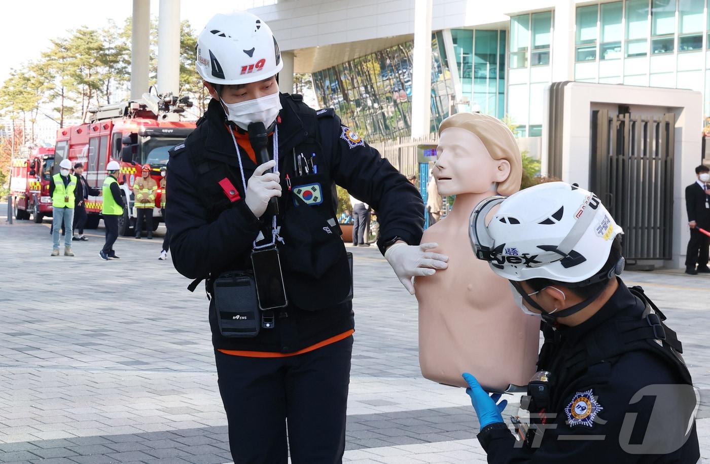 본문 이미지 - 27일 세종시 어진동 정부세종청사 중앙동에서 열린 화재 대비 민방위 훈련에서 세종 남부소방서 대원들이 53m 고가 소방차와 무인파괴 방수차를 이용한 고층 화재 진압 시연을 마친 뒤 심폐소생술 및 소화기 사용법을 교육하고 있다. 2025.10.28/뉴스1 ⓒ News1 김기남 기자