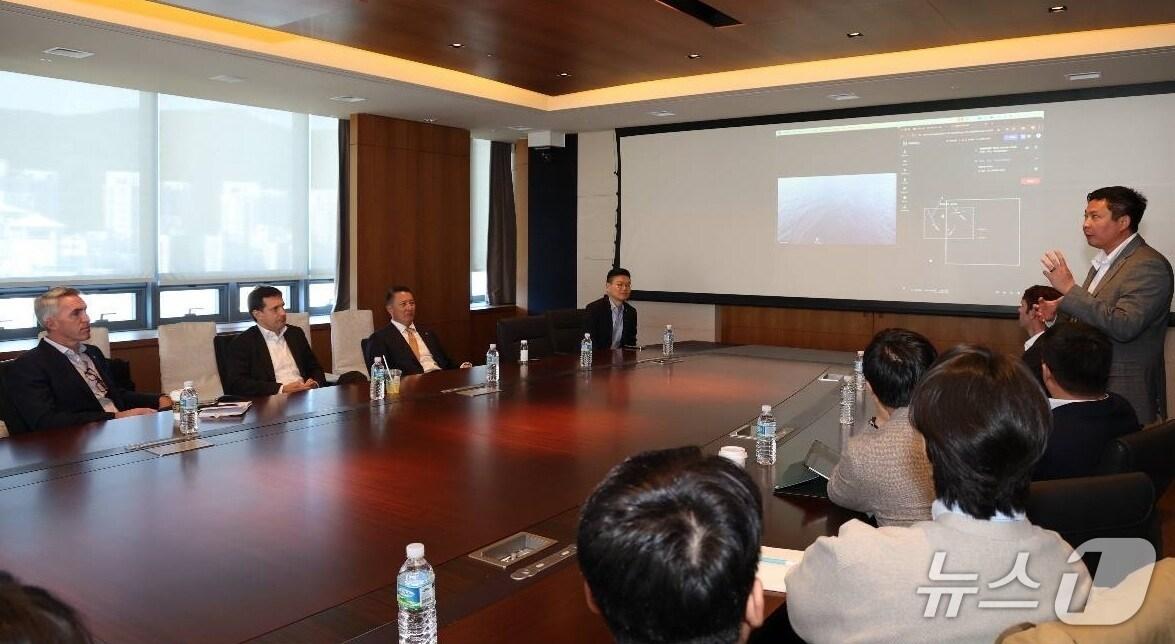 본문 이미지 - 폴 르윈 해벅AI CEO(맨 오른쪽 발표자)가 한화 임직원들에게 하와이 앞 바다에 대기중인 해벅AI의 무인수상정을 한화오션 거제사업장에서 원격통제하는 기술 시연을 선보이고 있다(한화시스템 제공)