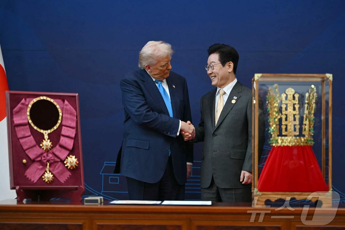 이재명 대통령이 29일 경북 경주박물관에서 열린 한미 공식 환영식에서 도널드 트럼프 미국 대통령에게 무궁화 대훈장 수여와 천마총 금관 모형을 선물한 뒤 악수하고 있다. ⓒ AFP=뉴스1