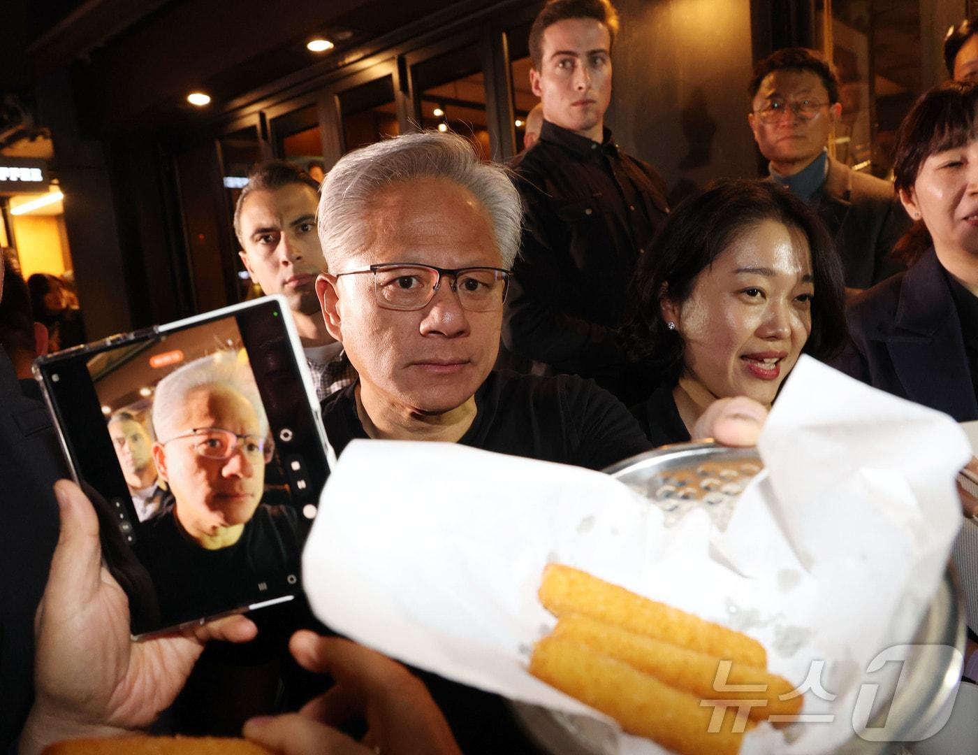 젠슨 황 엔비디아 최고경영자가 30일 이재용 삼성전자 회장, 정의선 현대자동차그룹 회장과 서울 강남구 깐부치킨에서 치킨 회동 중 치즈스틱을 시민들에게 내밀고 있다. (공동취재) 2025.10.30/뉴스1 ⓒ News1 김진환 기자