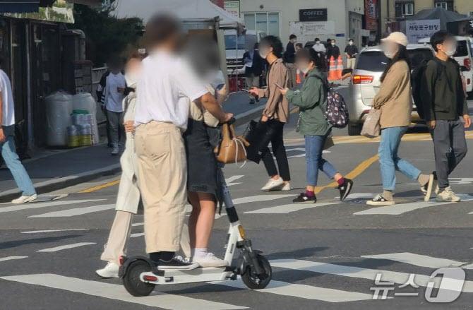 본문 이미지 - 서울의 한 횡단보도에서 시민들이 승차 정원을 초과해 전동킥보드를 타고 있다. / 뉴스1 ⓒ News1