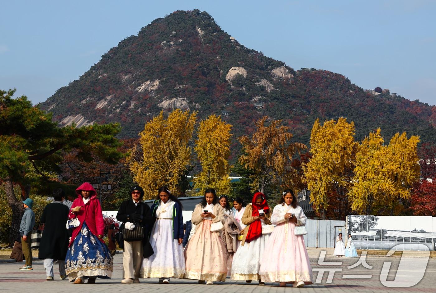 포근한 가을 날씨를 보인 11일 서울 종로구 국립고궁박물관에서 한복을 입은 관광객들 뒤로 단풍이 곱게 물들어 있다. 2025.11.11/뉴스1 ⓒ News1 김민지 기자