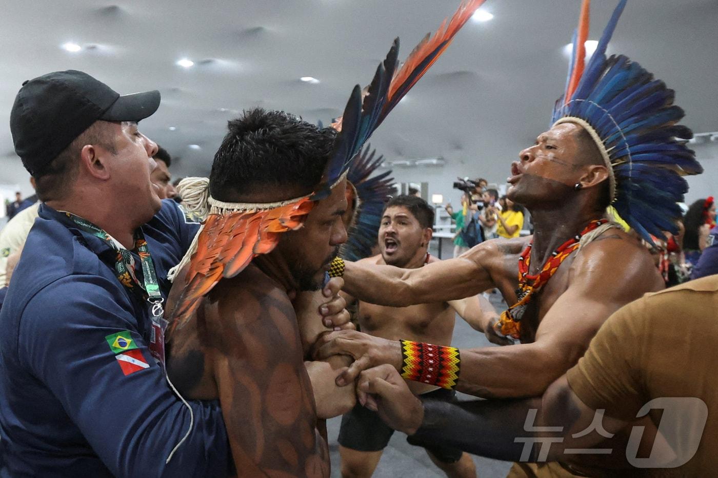 An Indigenous demonstrator is held by a staff member as protesters force their way into the venue hosting the UN Climate Change Conference &#40;COP30&#41;, in Belem, Brazil, November 11, 2025. REUTERS/Anderson Coelho TPX IMAGES OF THE DAY ⓒ 로이터=뉴스1