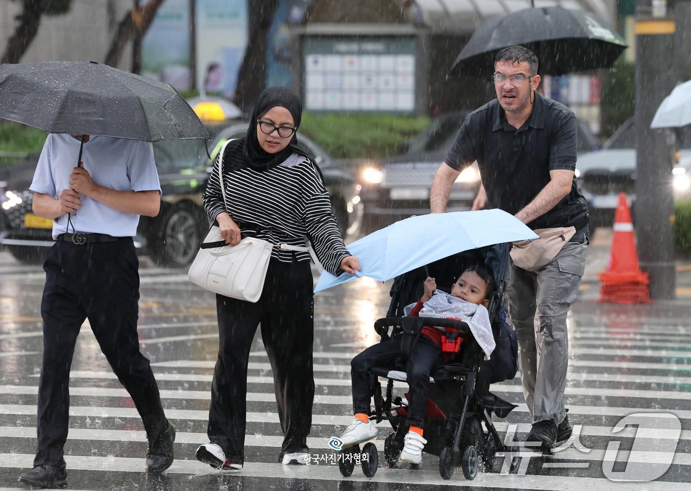 요란한 가을비가 내린 16일 오후 서울 중구 서울시청 앞을 지나는 외국인 부모가 유모차를 탄 아이에게 우산을 씌워준 채 급히 발걸음을 옮기고 있다.