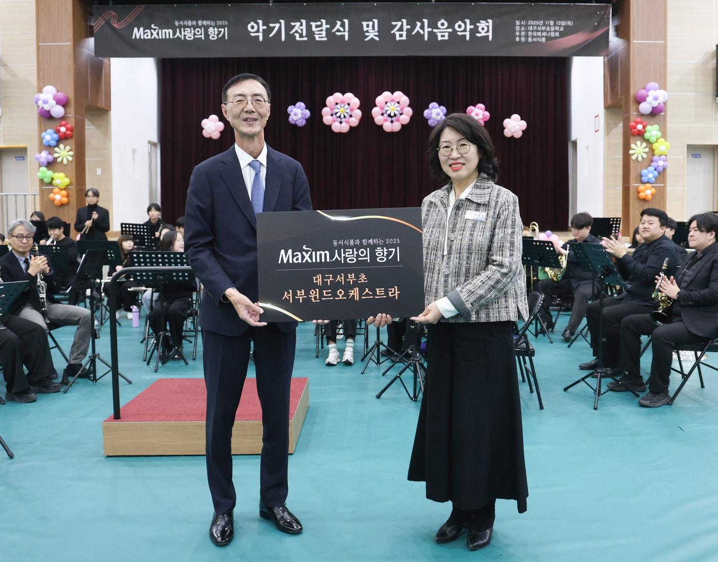 본문 이미지 - 13일 대구서부초등학교에서 열린 '제18회 맥심 사랑의 향기' 행사에서 (왼쪽)최상인 동서식품 홍보상무와 이보경 대구서부초등학교 교장이 기념촬영을 하고 있다. 동서식품 제공)