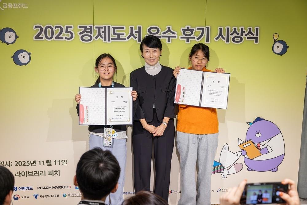 본문 이미지 - &#39;2025 쉬운글 경제도서 우수 후기 공모전&#39;시상식에서 대상 수상자와 시상자 신한카드 브랜드기획부 문유선 팀장이 기념촬영을 하고 있다. / 사진=피치마켓 제공