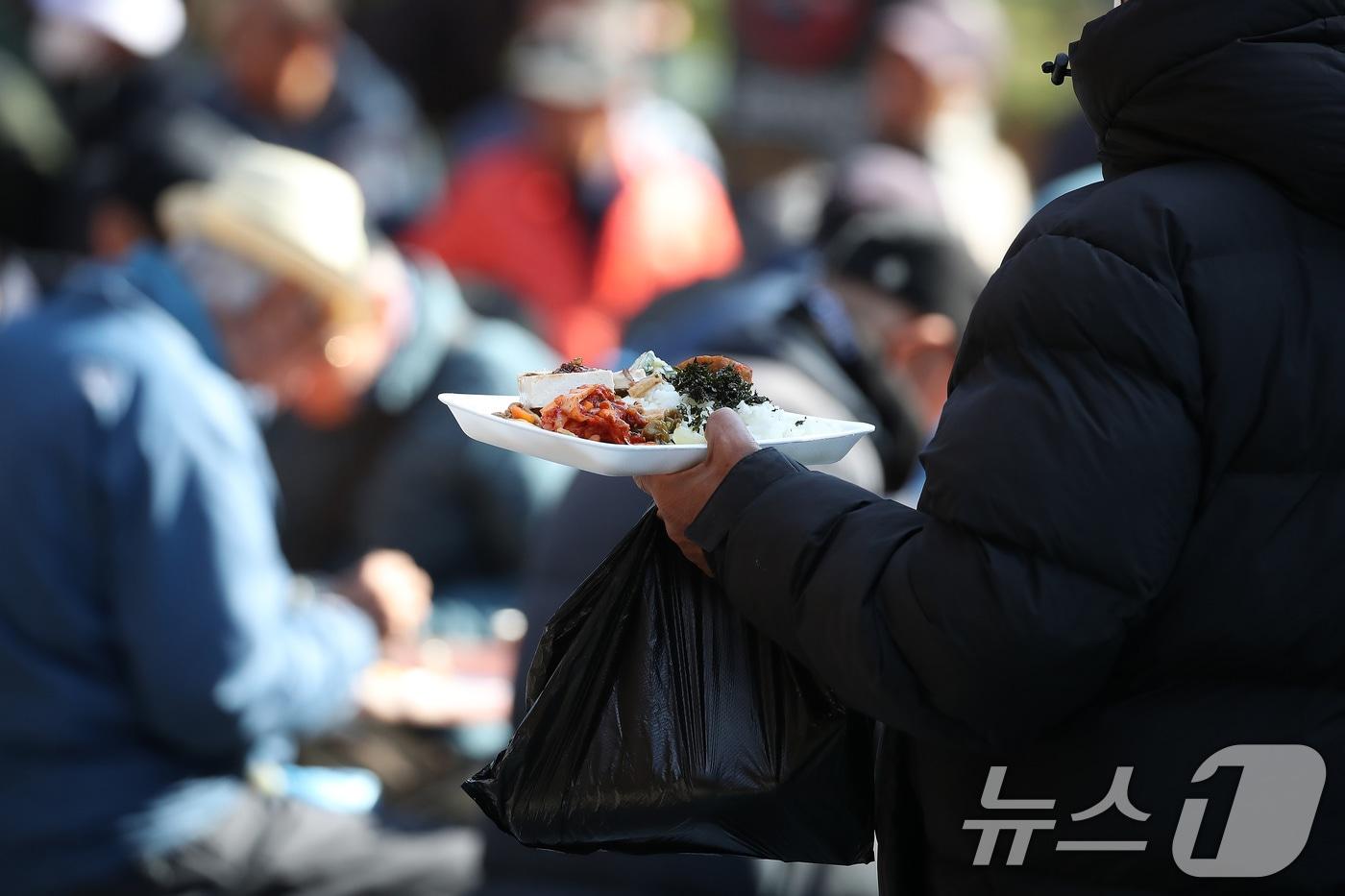 기온이 크게 내려가 초겨울 날씨를 보인 18일 대구 달서구 두류공원 사랑해밥차 무료급식소에서 점심 배식을 받은 시민이 식사할 곳을 찾고 있다. 2025.11.18/뉴스1 ⓒ News1 공정식 기자