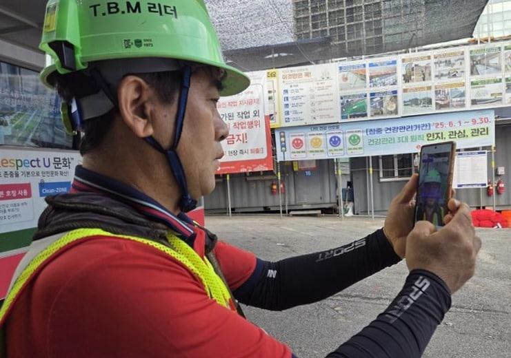 본문 이미지 -  롯데건설이 업계 최초로 개발한 &#39;건강체크 어플&#39;을 근로자가 사용하고 있다.&#40;롯데건설 제공&#41;/뉴스1 ⓒ News1