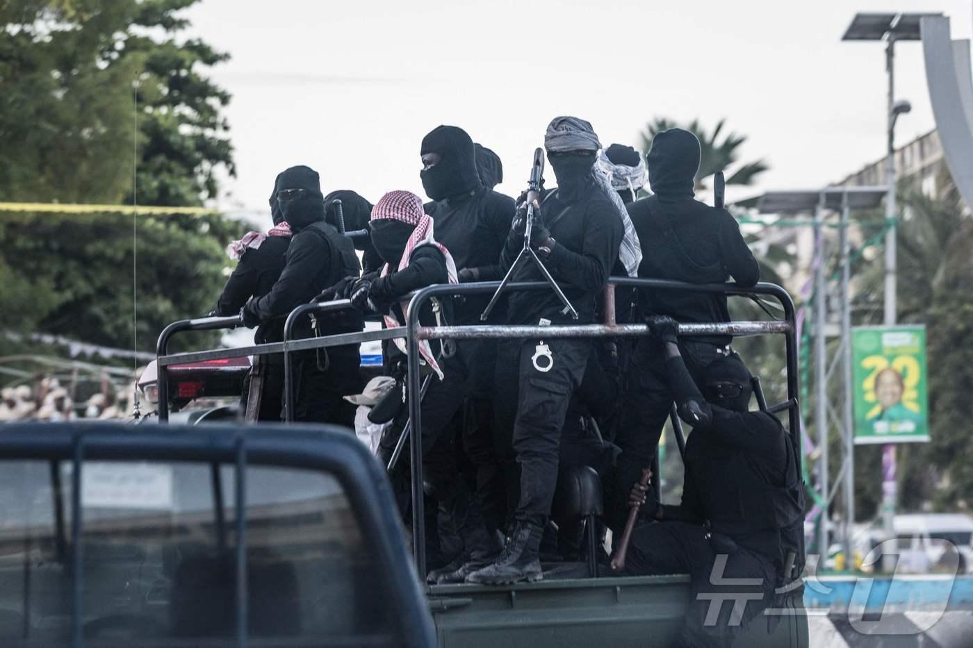 탄자니아 스톤타운에서 복면을 쓴 남성들이 집권 여당인 탄자니아혁명당&#40;CCM&#41; 소속 하산 대통령의 선거 포스터를 지나가고 있다. 2025.10.30. ⓒ AFP=뉴스1