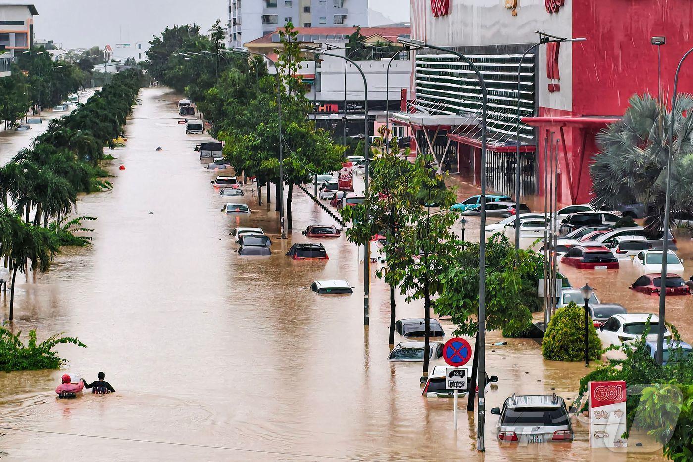 20일&#40;현지시간&#41; 베트남 카인호아성 나트랑에서 사람들이 침수된 차량 근처를 헤치고 있다. 2025.11.20. ⓒ AFP=뉴스1 ⓒ News1 이정환 기자