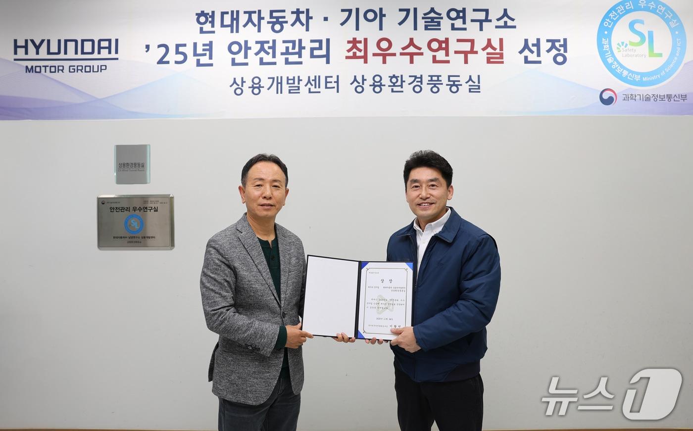  현대차∙기아는 과학기술정보통신부 주관 &#39;안전관리 우수연구실 인증&#39; 심사에서 남양연구소에 위치한 상용환경풍동실이 안전관리 최우수연구실로 선정됐다고 26일 밝혔다. 사진은 상용환경풍동실 앞에서 현대차∙기아 상용LCM담당 박상현 부사장, 상용연비운전성시험팀 이강웅 책임연구원이 기념사진을 찍는 모습.&#40;현대차∙기아 제공&#41;
