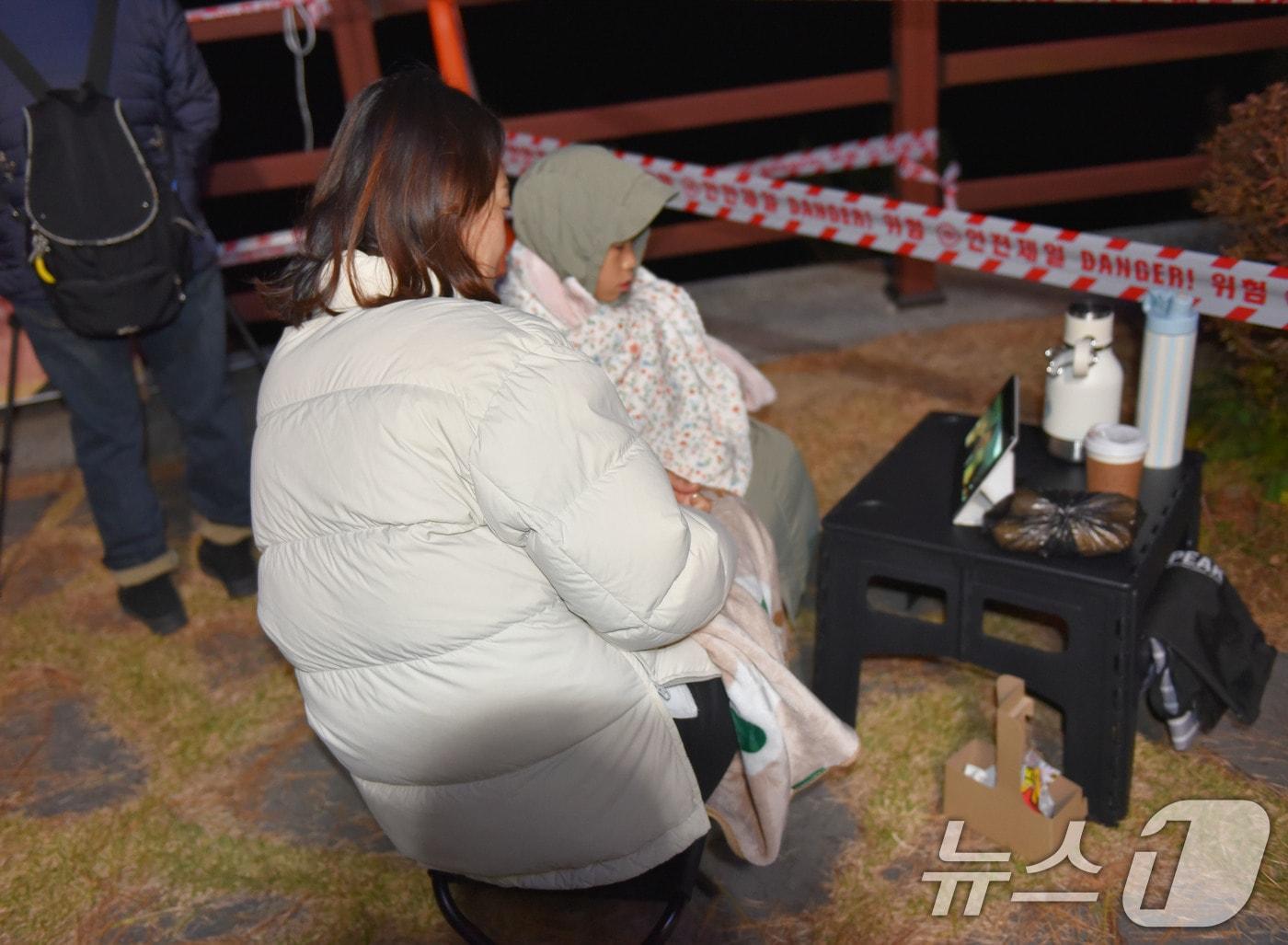 본문 이미지 - 누리호 4차 발사를 4시간 앞둔 26일 오후 9시쯤 아들과 함께 고흥우주발사전망대를 찾은 가족이 명당 자리를 잡고 유투브를 시청하고 있다. ⓒ News1 김성준 기자