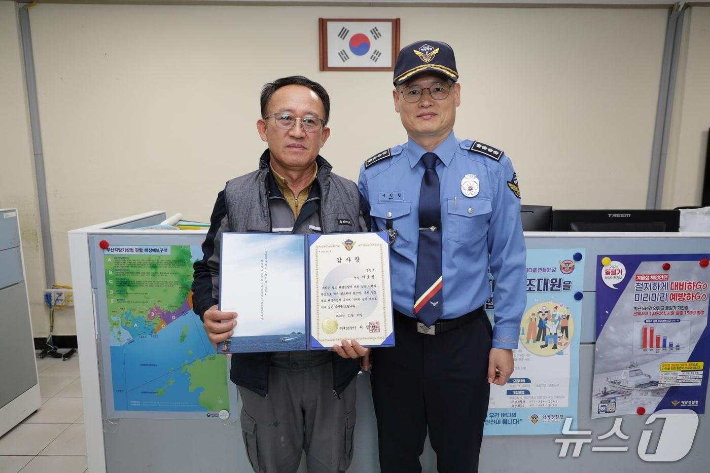 부산해경과 추락한 여성을 구조한 이호성 선장(왼쪽)이 감사장 수여가 끝난 뒤 기념사진을 찍고 있다.(부산해경 제공. 재판매 및 DB 금지)