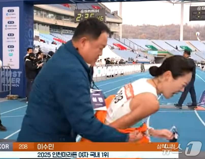 본문 이미지 - 지난 23일 인천 송도에서 열린 &#39;2025 인천국제마라톤&#39; 여자 국내부 1위 이수민 선수&#40;2시간 35분 41초&#41;가 결승선을 통과한 직후 다가가던 김완기 감독의 목에 심판 비표가 걸려있었다.&#40;KBS 유튜브 캡처, 재판매 및 DB금지&#41;