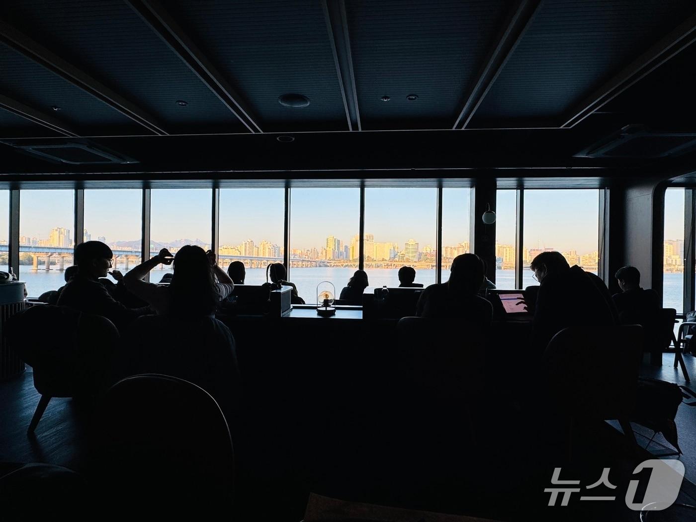 본문 이미지 - 정전으로 불이 꺼진 서울 여의도 한강버스 선착장 3층 스타벅스 내부. 일부 손님들이 어둑한 매장에서 한강을 바라보고 있다. 2025.11.3/뉴스1 ⓒ News1 한지명 기자