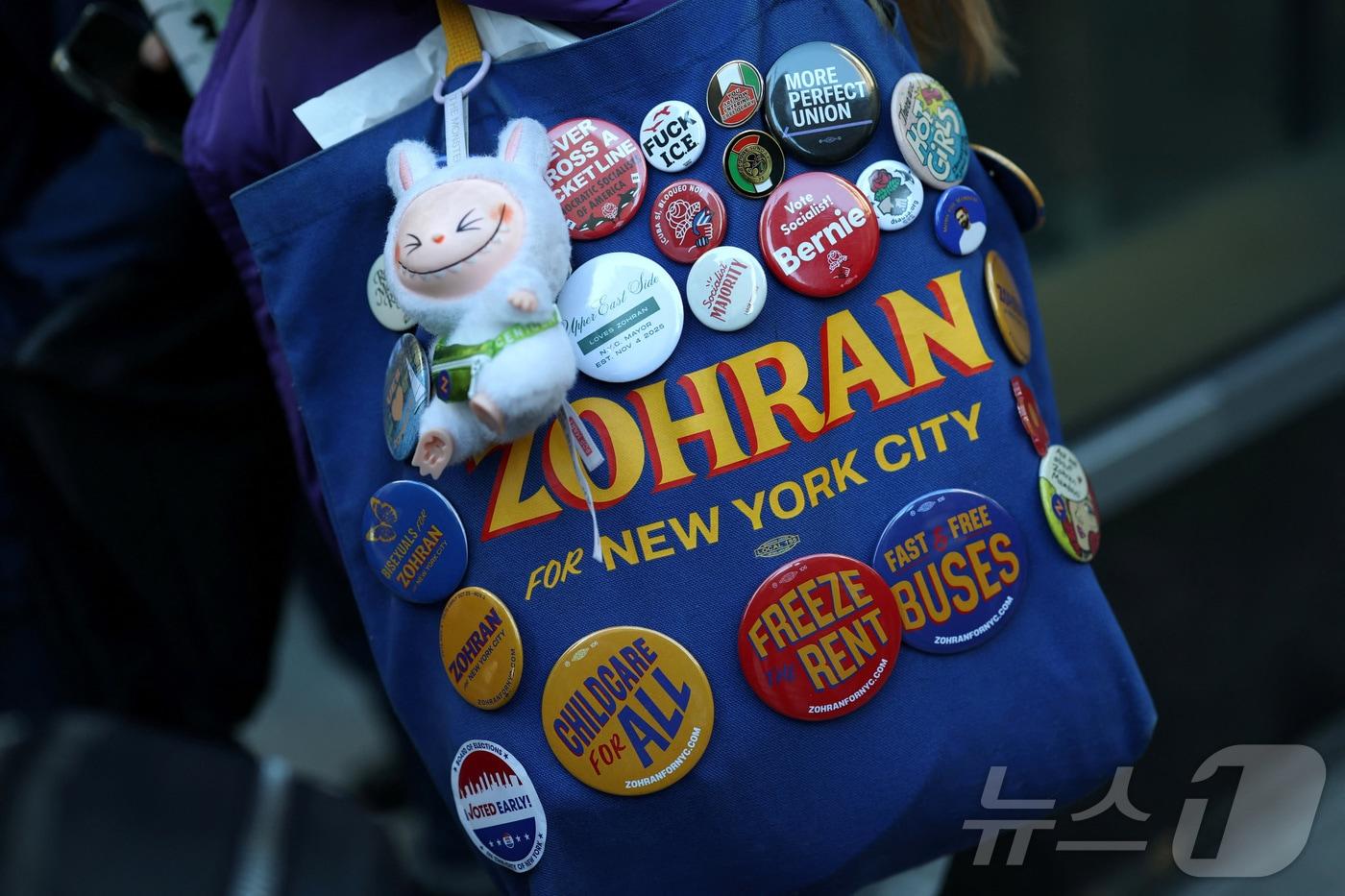 10월 27일&#40;현지시간&#41; 뉴욕 맨해튼 어퍼 이스트 사이드에서 조란 맘다니 민주당 뉴욕시장 후보가 사전투표 기간 중 선거 유세를 하는 가운데, 한 지지자가 맘다니를 지지하는 내용의 문구가 적힌 가방을 메고 이동하고 있다. 2025.10.27. ⓒ 로이터=뉴스1 ⓒ News1 윤다정 기자