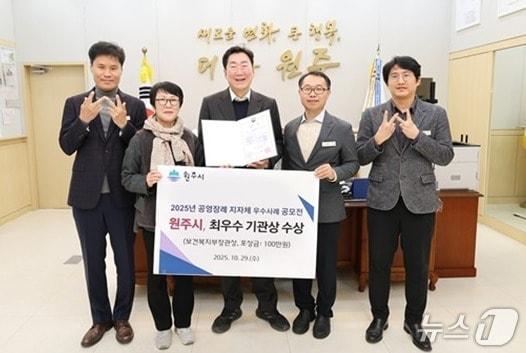 본문 이미지 - 강원 원주시가 최근 보건복지부 주관 &#39;2025년 공영장례 지자체 우수사례 공모전&#39;에서 최우수상을 받은 가운데, 원강수 원주시장을 비롯한 시 관계자들이 원주시청 시장 집무실에서 이를 기념하는 사진 촬영을 하고 있다. &#40;원주시 제공. 재판매 및 DB금지&#41; 2025.11.4/뉴스1