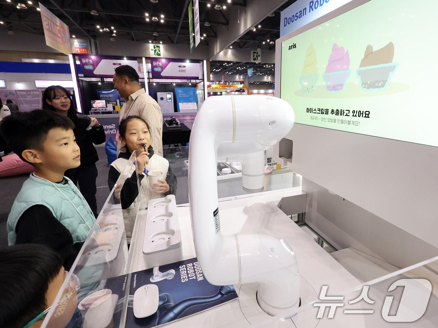 본문 이미지 - 5일 경기 고양시 일산서구 킨텍스에서 열린 '2025 디지털퓨처쇼'에서 ‘두산로보틱스’의 아이스크림 로봇 ‘아리스’가 관람객에게 아이스크림을 건네고 있다. 2025.11.5/뉴스1 ⓒ News1 황기선 기자