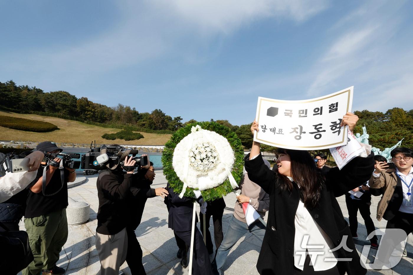 장동혁 국민의힘 대표가 6일 광주를 찾아 국립 5·18민주묘지를 참배하기 위해 들어서자 광주전남촛불행동 회원들이 당대표 조화을 치우고 있다. 2025.11.6/뉴스1 ⓒ News1 김태성 기자