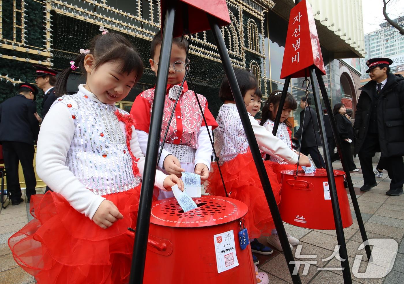 1일 부산 부산진구 롯데백화점 부산본점 정문 앞 광장에서 열린 구세군 자선냄비 시종식에서 축하공연을 펼친 어린이들이 자선냄비에 돈을 넣고 있다. 2025.12.1/뉴스1 ⓒ News1 윤일지 기자