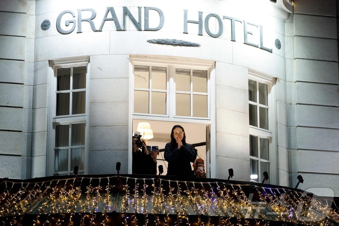 2025년 노벨평화상 수상자인 베네수엘라 야권 지도자 마리아 코리나 마차도가 11일&#40;현지시간&#41; 노르웨이 오슬로에 도착한 뒤 호텔 발코니에서 모습을 드러냈다. 늦게 도착해 시상식에 참석하지 못한 마차도는 이날 별도의 기자회견을 갖는다. ⓒ AFP=뉴스1