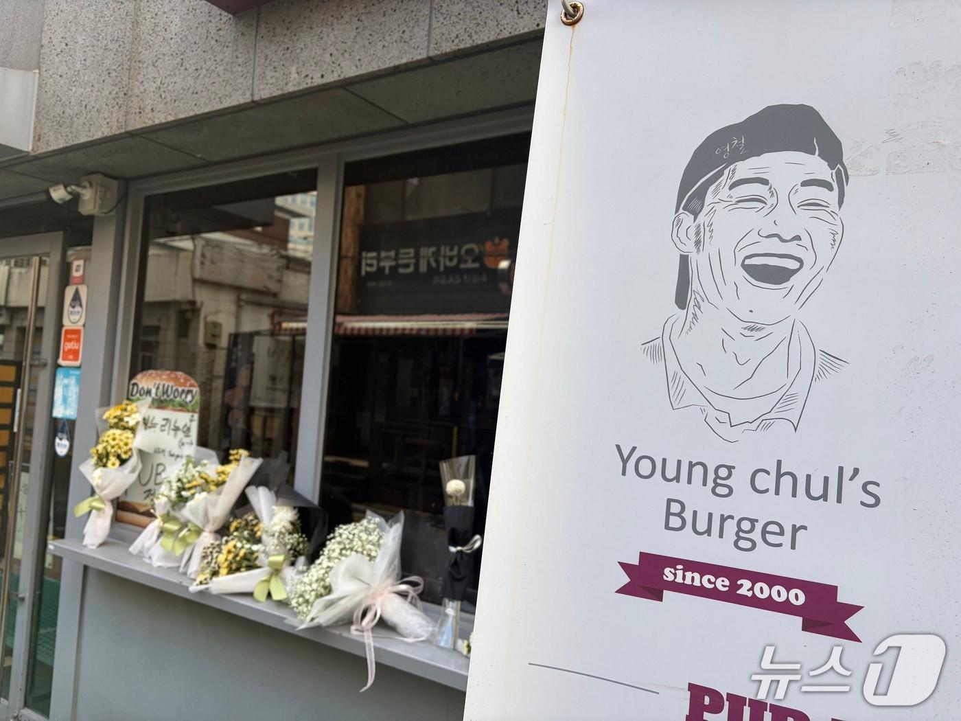 본문 이미지 - 14일 오전 서울 성북구 안암동에 있는 영철버거 앞에 흰 꽃다발이 줄지어 놓였다. 2025.12.14/ 뉴스1 김종훈 기자