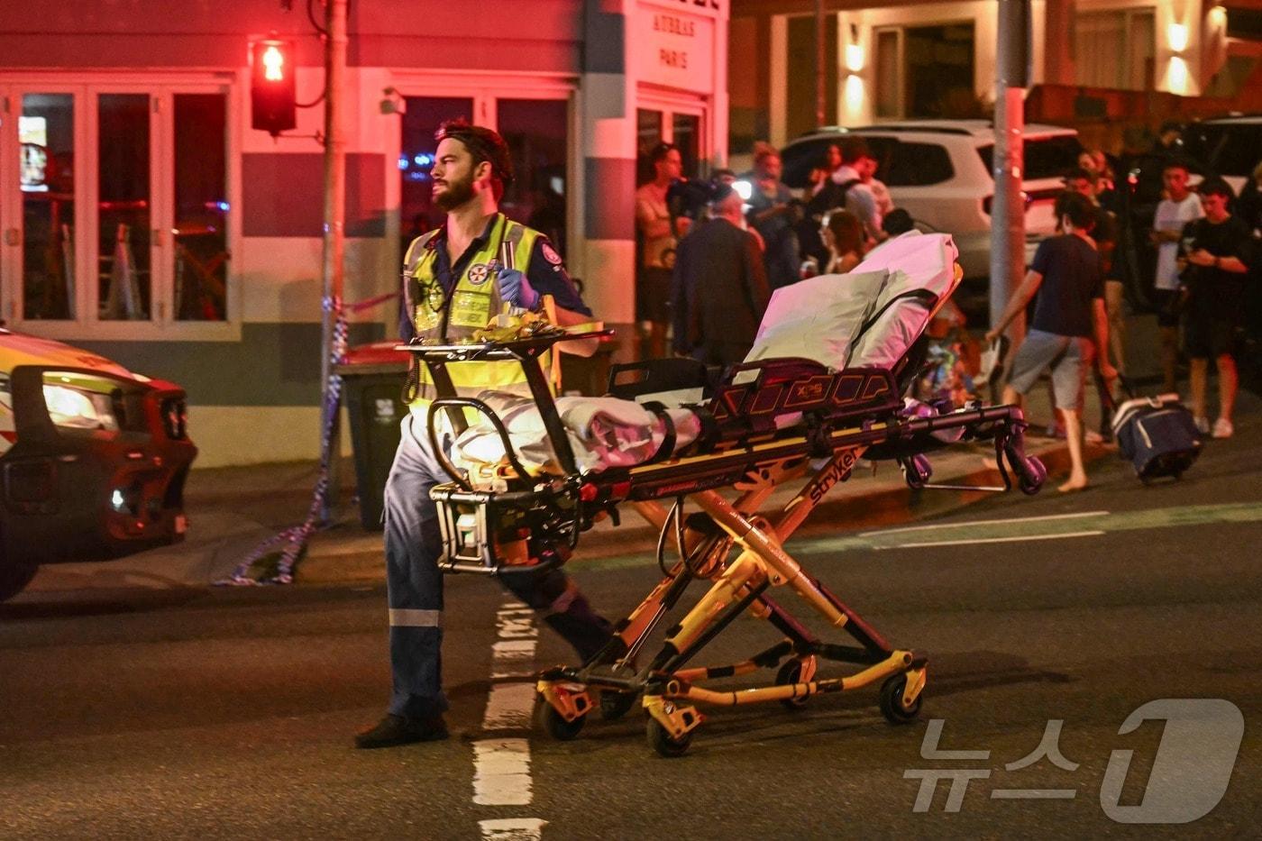 14일(현지시간) 호주 시드니 본다이 비치에서 총격 사건이 발생한 가운데, 의료진들이 피해자들을 병원으로 후송하고 있다. ⓒ AFP=뉴스1