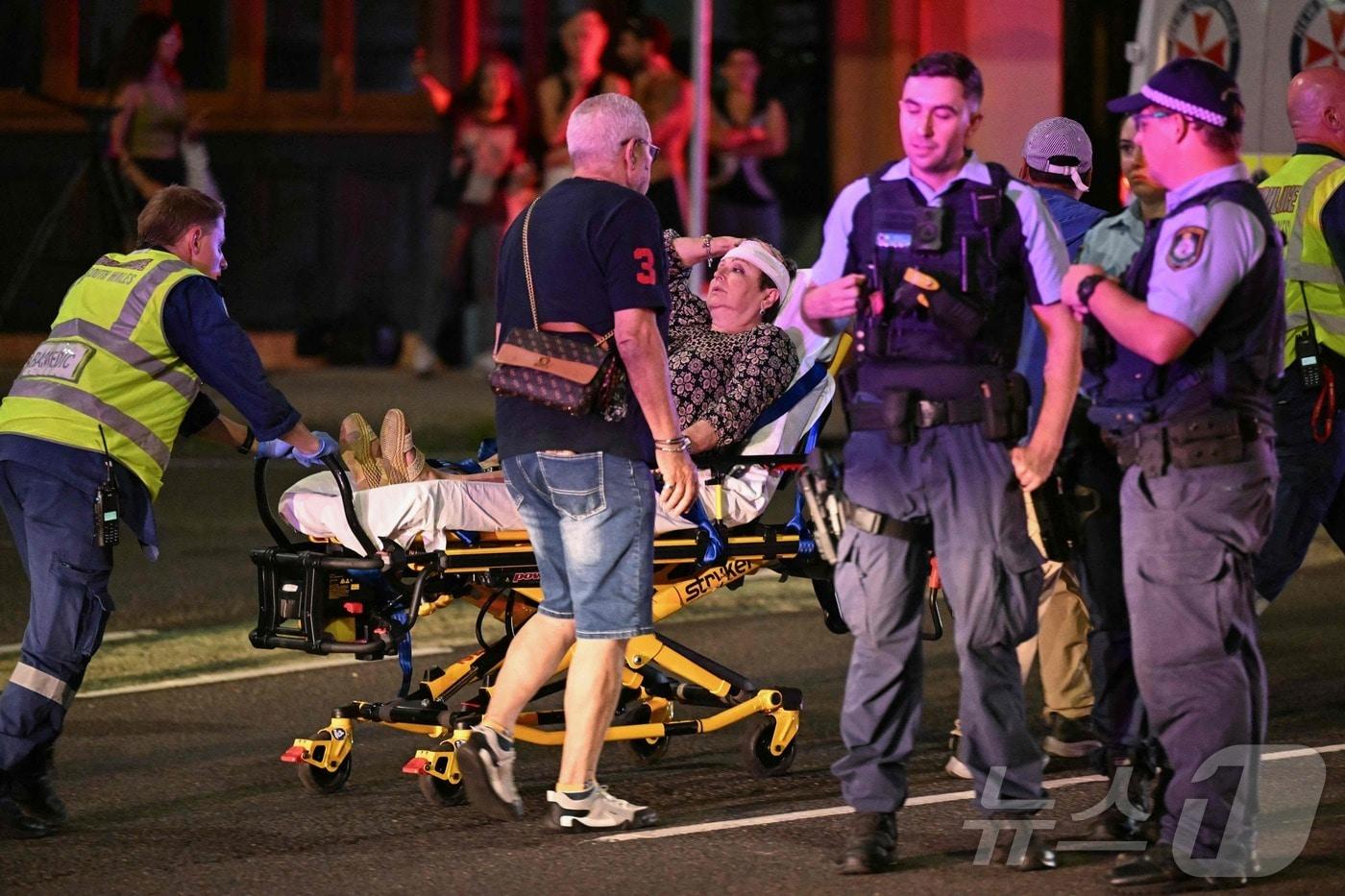 14일(현지시간) 호주 시드니 본다이 비치에서 총격 사건이 발생한 가운데, 의료진들이 피해자들을 병원으로 후송하고 있다. ⓒ AFP=뉴스1