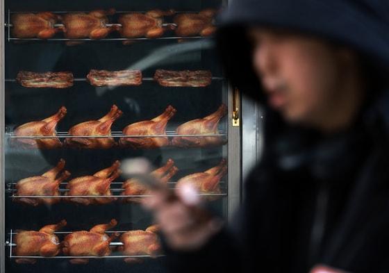 본문 이미지 - 치킨을 판매할 때 조리 전 닭고기 무게를 소비자에게 고지해야 하는 '치킨 중량표시제'가 본격적으로 시행되는 15일 서울 시내의 한 치킨매장 앞으로 시민이 지나가고 있다. '치킨 중량표시제'는 치킨의 가격은 그대로 두고 무게를 줄이는 꼼수 인상하는 '슈링크플레이션'을 방지하기 위해 공정거래위원회, 식품의약품안전처 등 관계 부처가 합동으로 마련했으며 bhc, BBQ치킨, 교촌치킨, 처갓집양념치킨 등 상위 10개 브랜드가 매장 및 배달 주문 메뉴판에 닭고기의 조리 전 총중량을 명시해야 한다. 2025.12.15/뉴스1 ⓒ News1 이호윤 기자