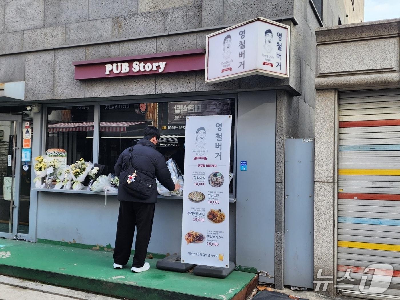 본문 이미지 - 15일 서울 성북구 소재 '영철버거' 앞에서 한 고려대학교 대학원생이 헌화하고 있다. 2025.12.15/ⓒ 뉴스1 권진영 기자