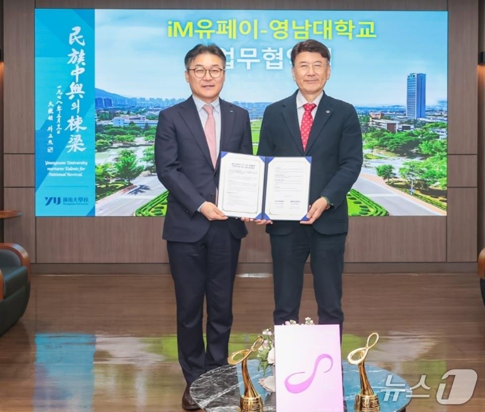 본문 이미지 - 윤재웅 iM유페이 대표이사(왼쪽)와 최외출 영남대 총장이 청년 교통복지 확대와 스마트 캠퍼스 구축을 위한 업무협약을 체결한 후 협약서를 펼쳐 보이고 있다.(iM뱅크 제공, 재판매 및 DB 금지)