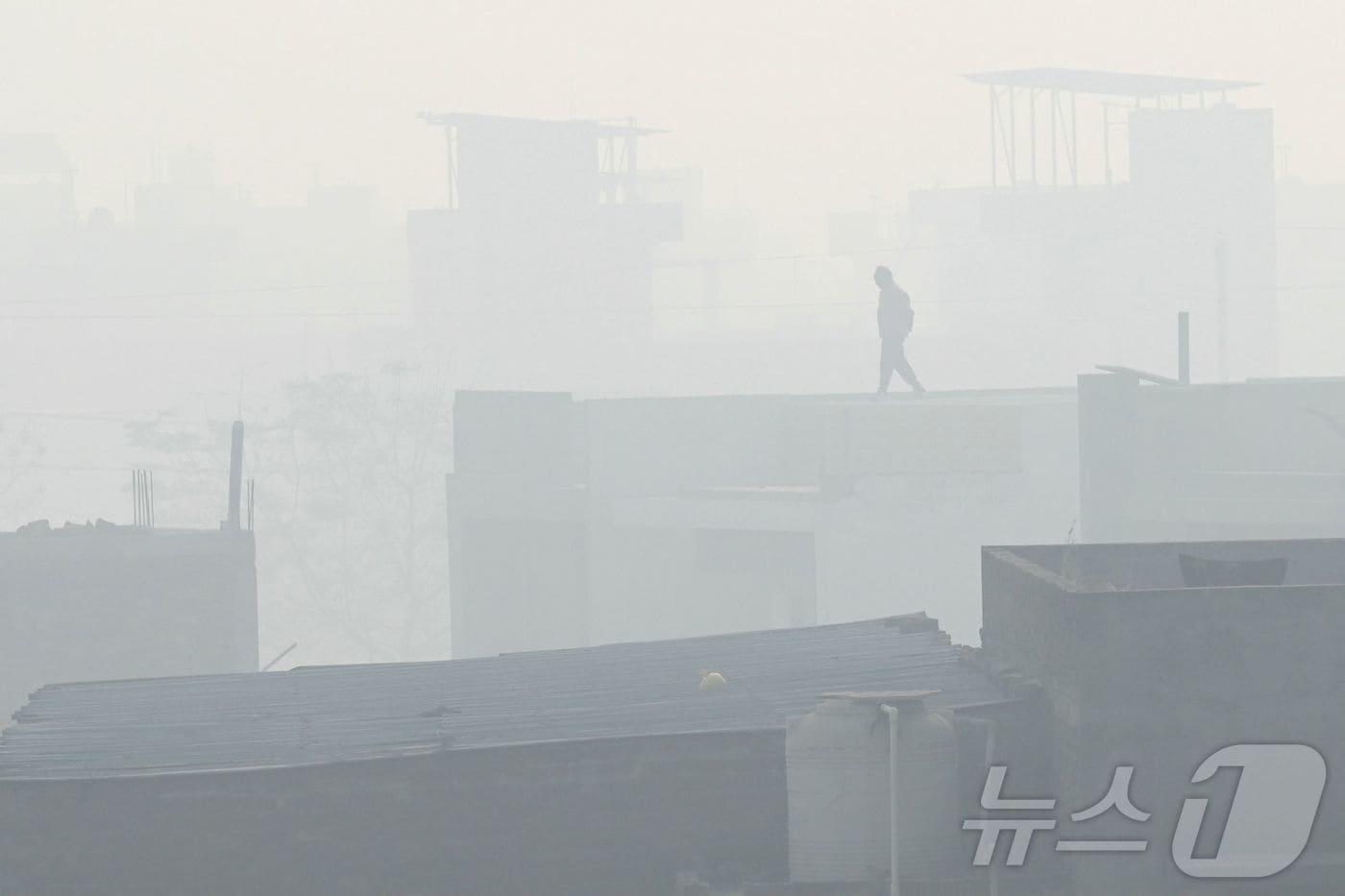 12일 인도 암리차르에서 한 남성이 스모그 속 공장 지붕 위를 걷고 있다.2025.12.12. ⓒ AFP=뉴스1