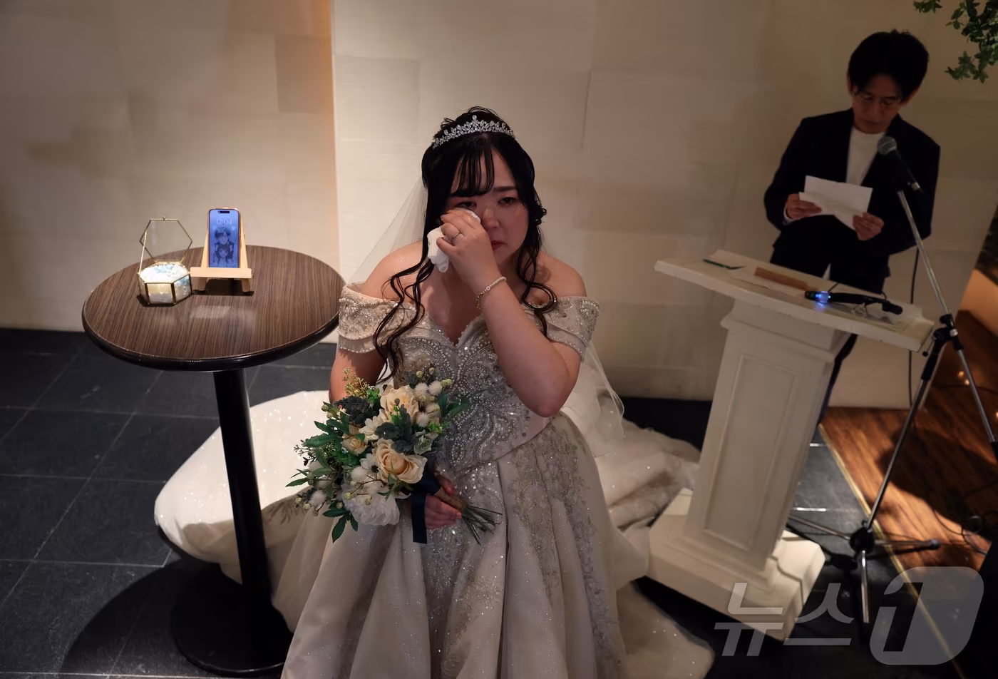 지난 10월 27일 일본 오카야마현에서 인공지능(AI)이 생성한 가상 캐릭터 '클라우스'와 결혼한 유리나 노구치(32)가 가상·2D 캐틱터 결혼 전문 설계사 나오키 오가사와라가 대독한 클라우스의 메시지를 들으며 눈물을 흘리고 있다. 2025.10.27 ⓒ 로이터=뉴스1 ⓒ News1 김지완 기자