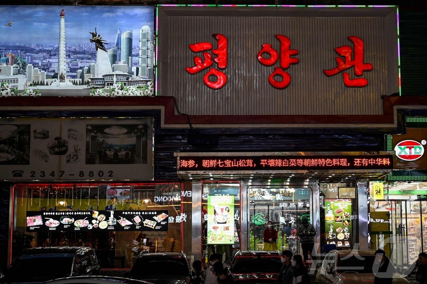 2023년 3월 31일 중국 북동부 랴오닝성 선양의 한 북한 마을에 있는 북한 식당 입구에 마스크를 쓴 북한 노동자가 서 있다. 2023.03.31. ⓒ AFP=뉴스1 ⓒ News1 이정환 기자