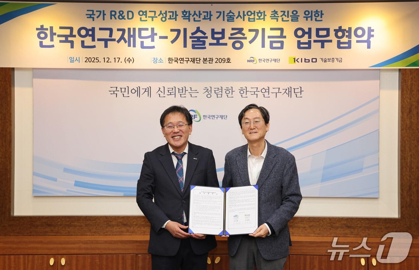 이상창 기술보증기금 이사(왼쪽)와 이석래 한국연구재단 사무총장이 17일 국가 연구개발(R&D) 우수성과 확산 및 기술사업화 촉진을 위한 업무협약을 체결하고 협약서를 들어보이고 있다.(한국연구재단 제공) /뉴스1