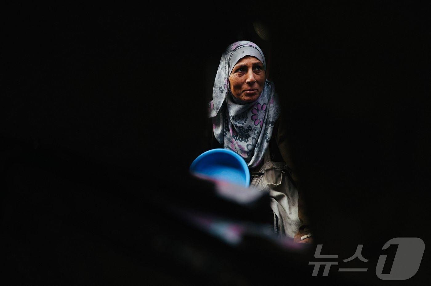 17일(현지시간) 팔레스타인 가자 지구 남부 칸 유니스의 자선 급식소 앞에서 한 팔레스타인 피난민 여성이 식량 배급을 기다리고 있다. 2025.12.17. ⓒ AFP=뉴스1 ⓒ News1 윤다정 기자