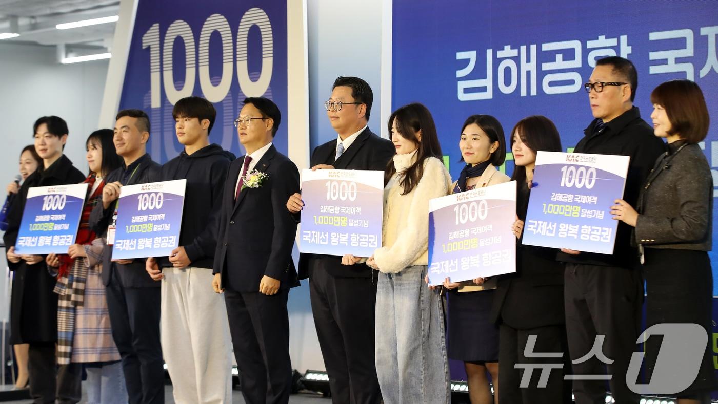 19일 오전 부산 강서구 김해국제공항 국제선 확충터미널에서 열린 '김해공항 국제여객 1000만 명 달성 기념행사'에서 남창희 한국공항공사 김해공항장이 1000만 번째 승객들에게 1000만 명 달성 기념 국제선 왕복 항공권을 전달한 뒤 함께 기념촬영을 하고 있다.2025.12.19/뉴스1 ⓒ News1 윤일지 기자