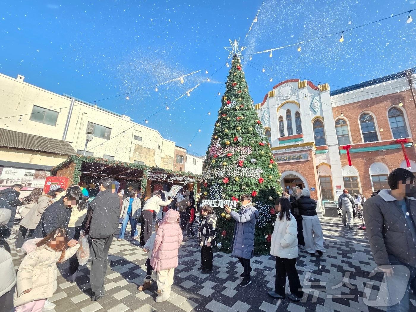 본문 이미지 - 21일 오후 2시께 전북 익산시 중앙동 익산근대역사관 광장에서 진행된 '인공 눈 퍼포먼스'를 시민들이 즐기고 있다.2025.12.21/뉴스1 문채연 기자 ⓒ News1 문채연 기자
