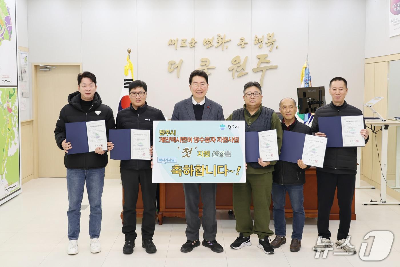 강원 원주시가 22일 시청 시장 집무실에서 개인택시 면허 양수 융자지원 사업 첫 지원자 5명을 축하하는 자리를 마련한 가운데, 이날 원강수 원주시장과 지원자 5명이 기념 사진을 촬영하고 있다. (원주시 제공. 재판매 및 DB금지) 2025.12.22/뉴스1