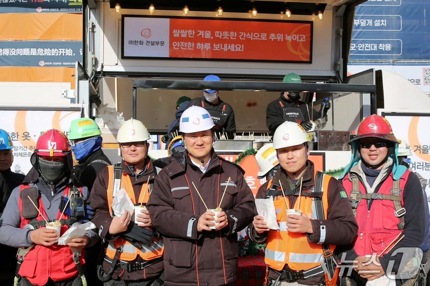 김우석 한화 건설부문 대표이사(가운데)가 건설현장 근로자들과 함께 ‘찾아가는 겨울간식차’의 호빵과 어묵을 즐기고 있다. (한화 건설부문 제공) /뉴스1 ⓒ News1