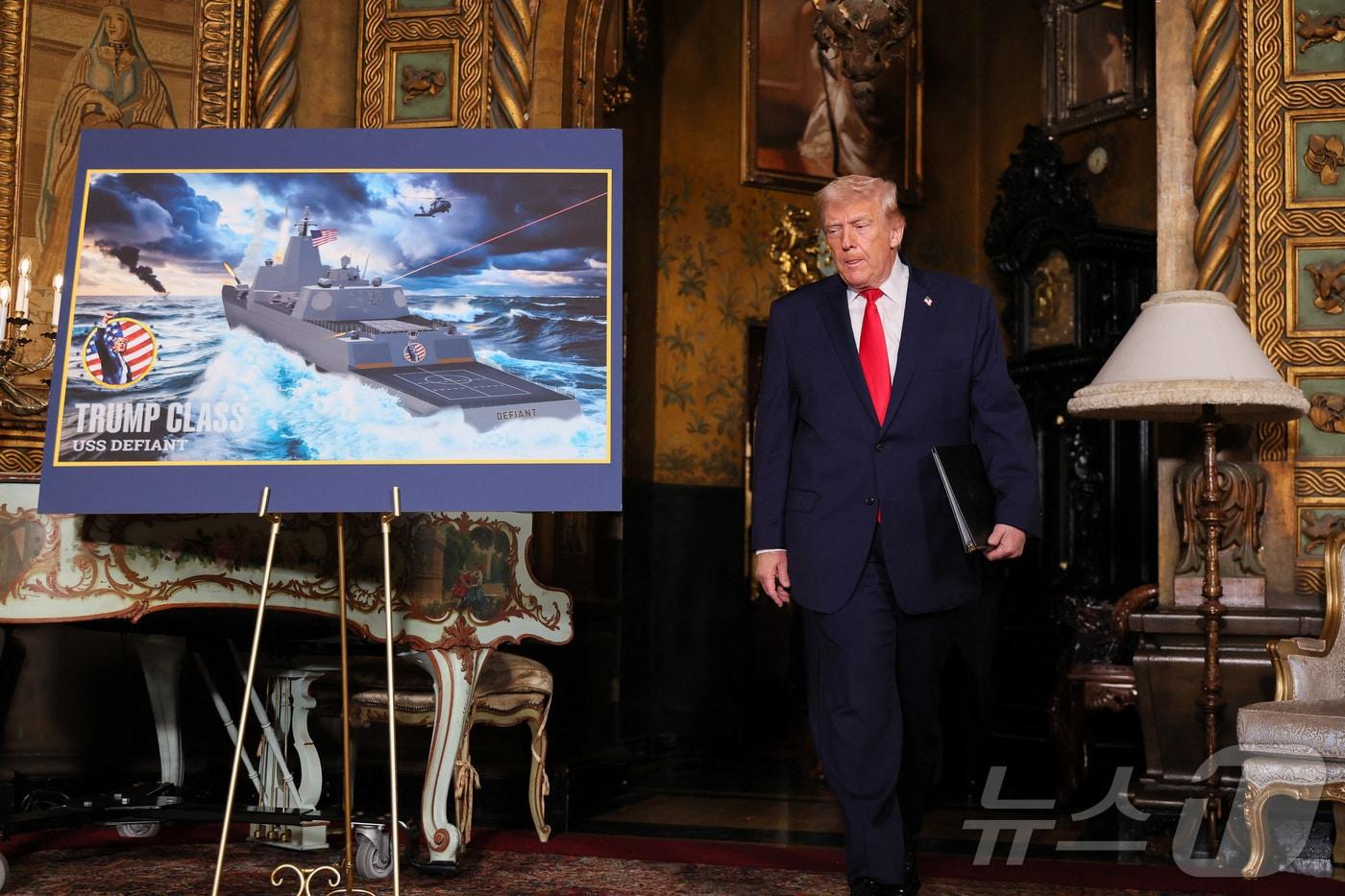 본문 이미지 - 22일(현지시간) 도널드 트럼프 미국 대통령이 플로리다주 팜비치 마러라고에서 해군의 신형 '황금 함대'(Golden Fleet) 관련 '트럼프급' 전투함 USS 디파이언트의 조감도를 지나고 있다. 2025.12.22. ⓒ 로이터=뉴스1 ⓒ News1 이정환 기자