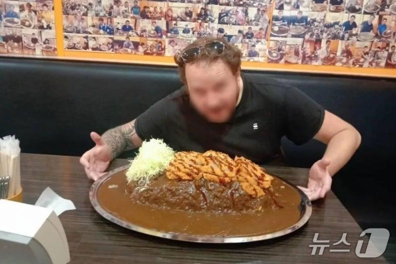 본문 이미지 -  도전자가 8㎏짜리 카레라이스 접시 앞에서 ‘성공적인’ 도전을 시작하기 전 포즈를 취했다. 그는 45분 안에 접시를 비웠지만 속임수를 쓴 것으로 나중에 드러났다. (사진: 골드 커리 방콕)