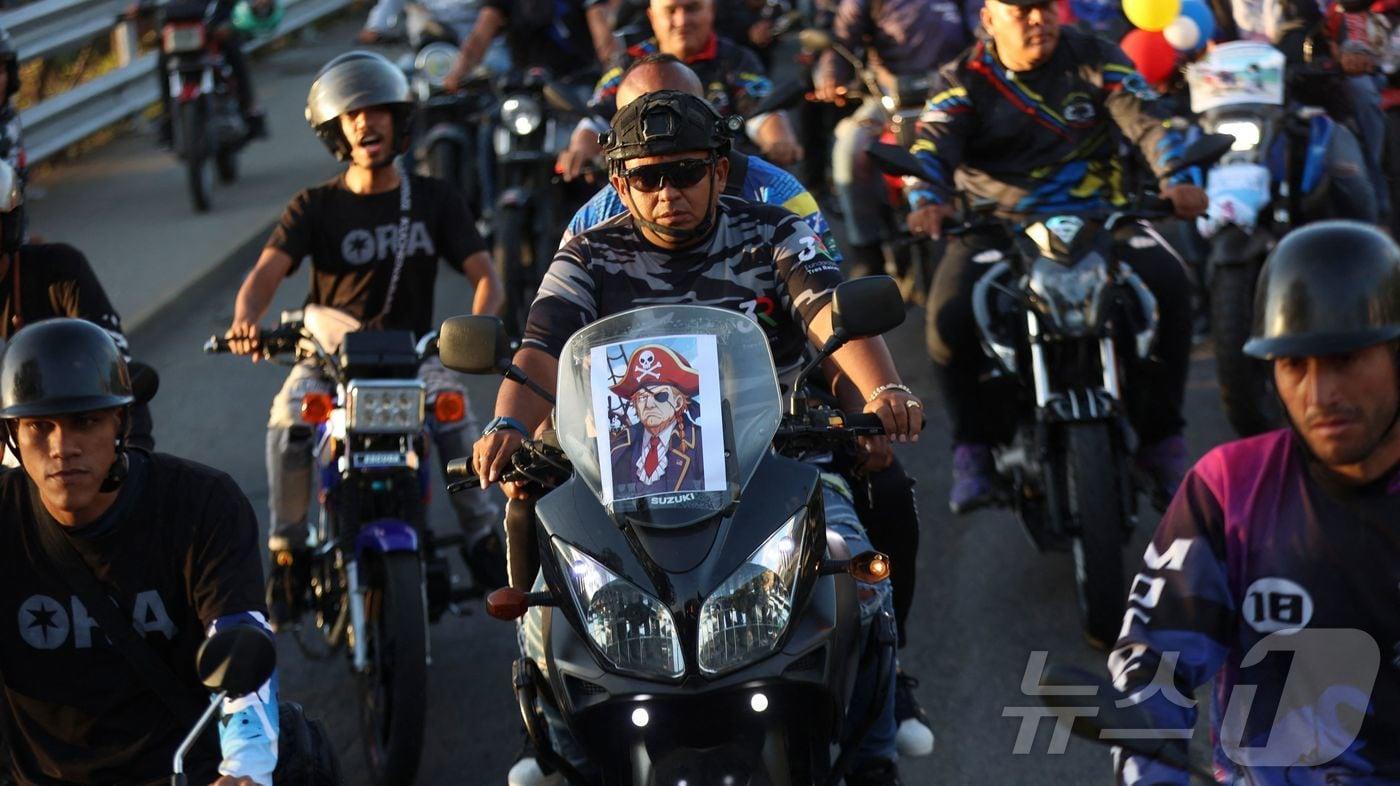 22일(현지시간) 베네수엘라 카라카스에서 미국에 항의하는 오토바이 행렬에 참여한 한 운전자가 해적 복장을 한 도널드 트럼프 미국 대통령의 사진을 오토바이에 부착했다. 이날 해적 복장을 한 오토바이 운전자 수십 명은 미국이 제재 대상 유조선에 대한 봉쇄 조치의 일환으로 베네수엘라산 석유를 실은 선박들을 나포한 것에 항의하며 카라카스 시내를 행진했다. 2025.12.22. ⓒ AFP=뉴스1