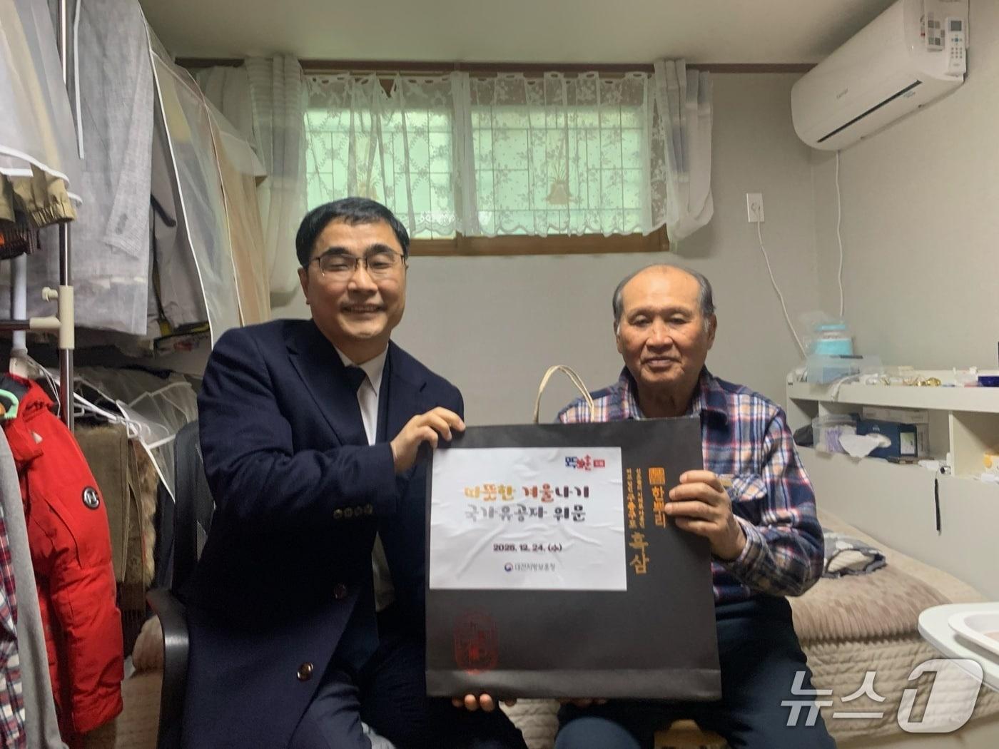 본문 이미지 - 오재덕 대전보훈청장(왼쪽)이 24일 국가유공자 가정을 방문해 위문품을 전달했다.(대전보훈청 제공) /뉴스1