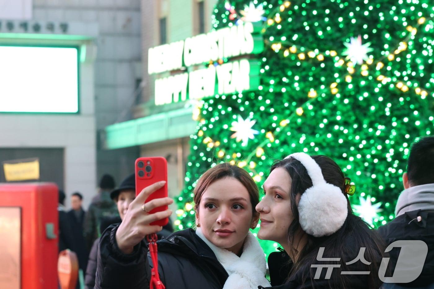 크리스마스 이브인 24일 오후 서울 중구 명동을 찾은 외국인관광객들이 성탄트리를 배경으로 '셀카'를 찍고 있다. 2025.12.24/뉴스1 ⓒ News1 황기선 기자
