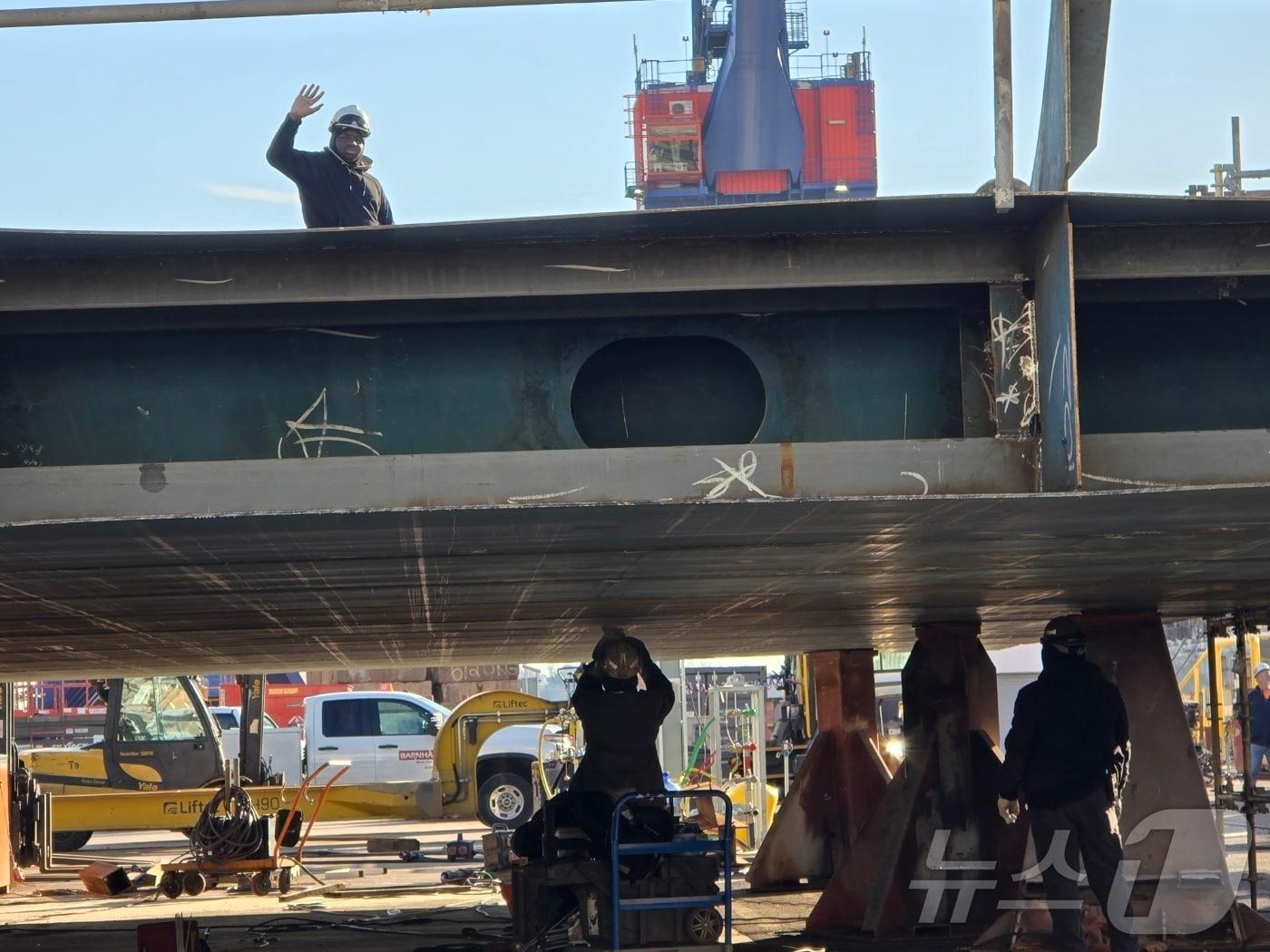 본문 이미지 - 지난 22일(현지시간) 미국 펜실베이니아주 필라델피아에 위치한 한화필리조선소에서 작업 중이던 근로자가 취재진을 향해 손을 들어 인사하고 있다. 2025.12.25. ⓒ News1 류정민 특파원