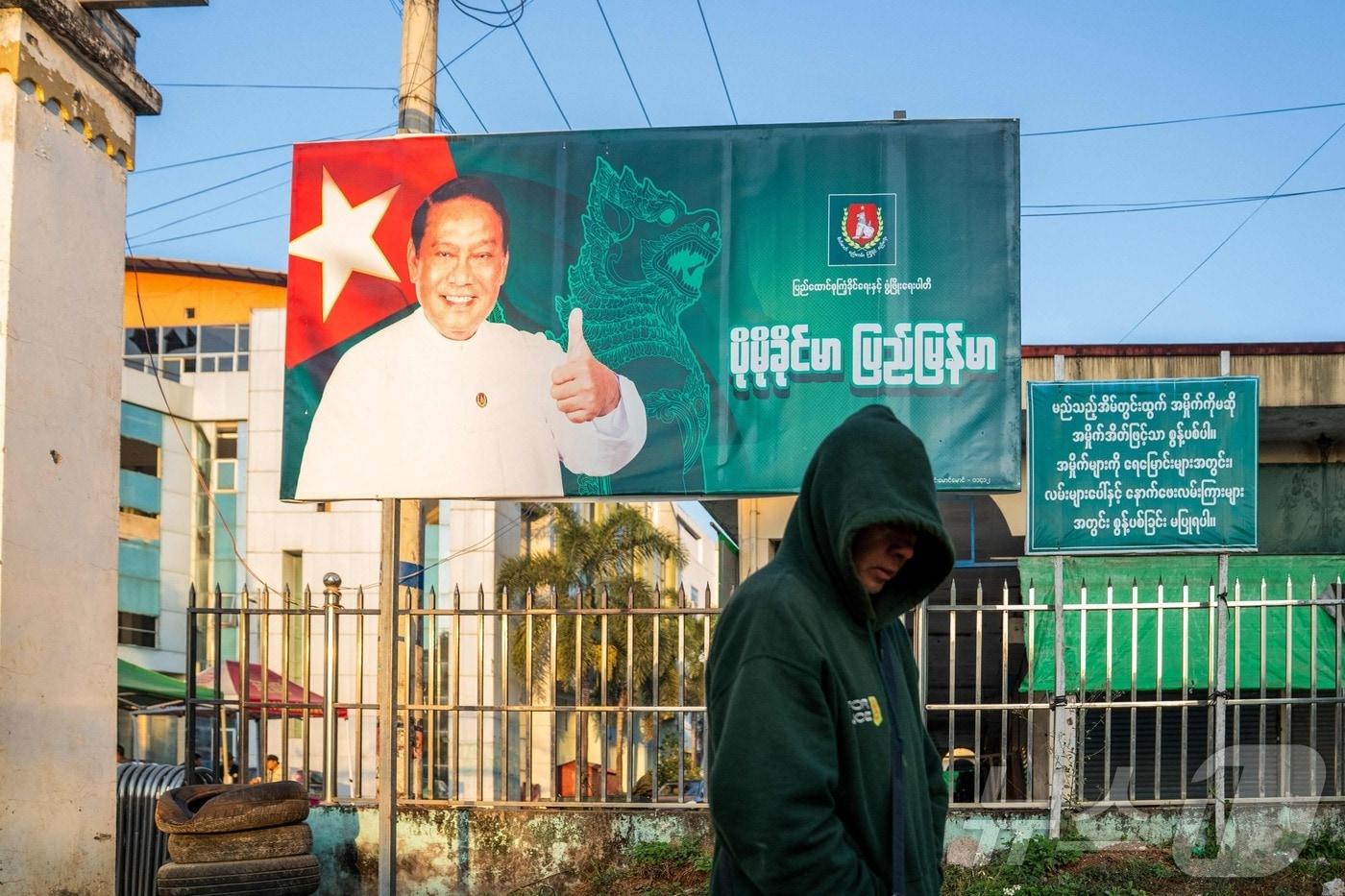  20일, 미얀마 북부 샨주 라시오에서 한 남성이 군부의 대리정당 통합연대발전당(USDP) 의장 킨 이의 사진이 걸린 선거 운동 광고판 앞을 지나가고 있다. ⓒ AFP=뉴스1