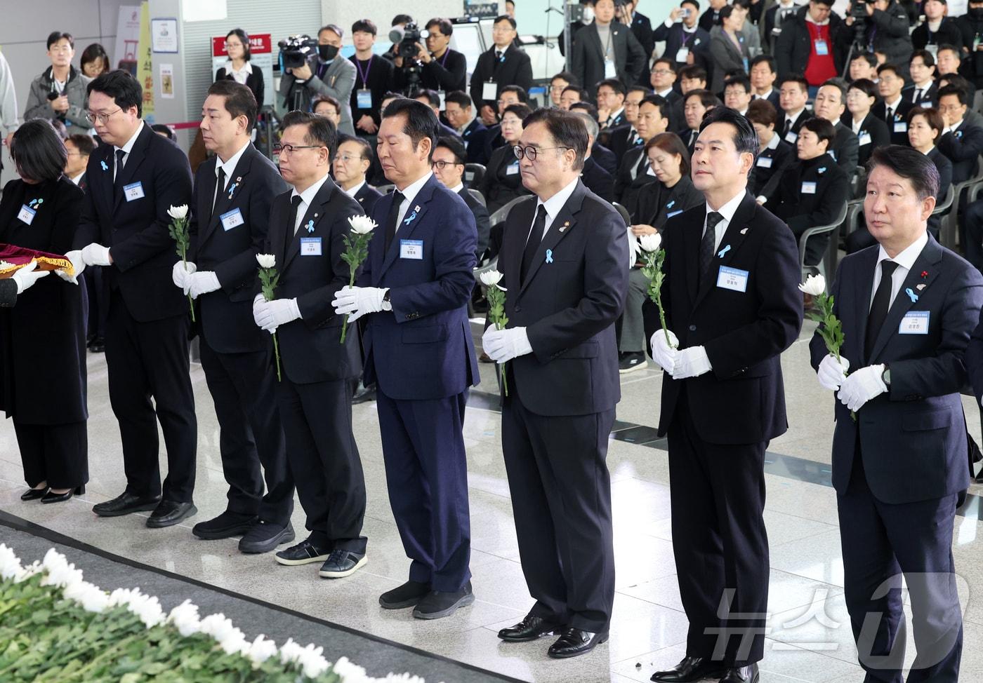 29일 오전 전남 무안국제공항에서 열린 12·29 제주항공 여객기 참사 1주기 추모식에서 우원식 국회의장을 비롯한 국회 측 참석자들이 헌화하기 위해 국화를 들고 있다. 2025.12.29/뉴스1 ⓒ News1 사진공동취재단
