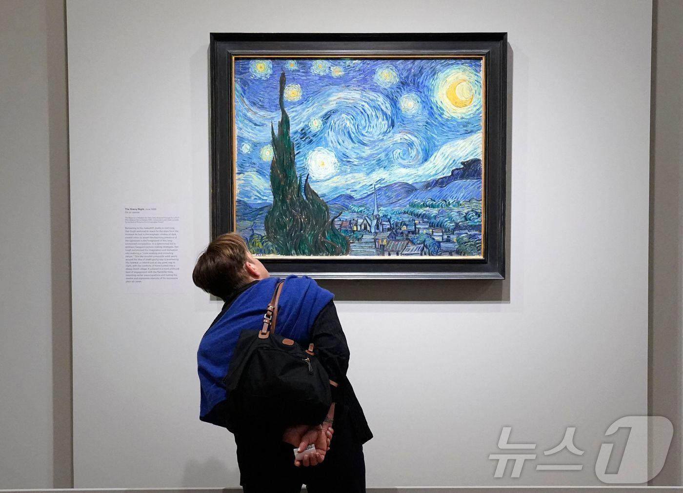 본문 이미지 - 뉴욕 메트로폴리탄 미술관 5번가에서 열린 ‘반 고흐의 사이프러스’ 전시 프레스 프리뷰에서 한 관람객이 빈센트 반 고흐의 대표작 ‘별이 빛나는 밤’을 바라보고 있다.2023.05.15.ⓒ AFP=뉴스1